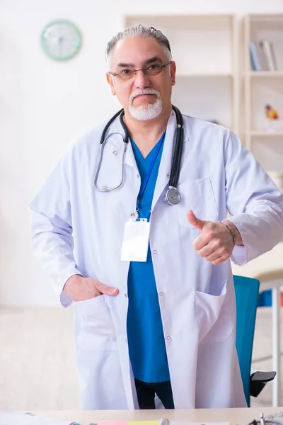 Oude mannelijke arts werkzaam in de kliniek — Stockfoto