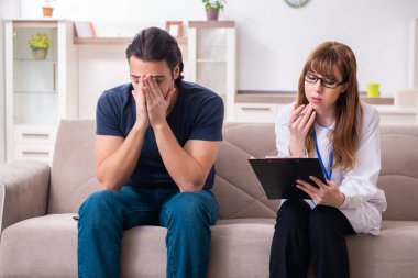 Genç bir erkek hasta kadın psikologla konuşuyor. 