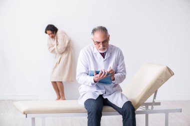 Genç hastayı muayene eden yaşlı erkek doktor psikiyatristi 