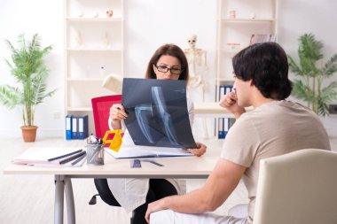 Kadın doktor hastaları goniyometre ile kontrol ediyor.