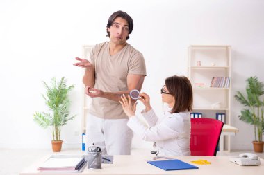 Kadın doktor hastaları goniyometre ile kontrol ediyor.