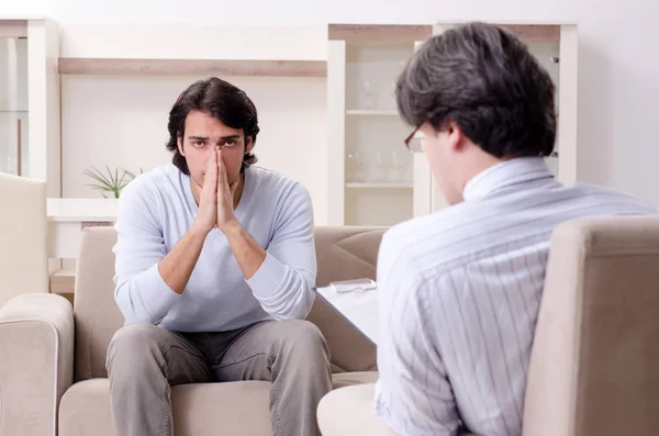 Jovem paciente do sexo masculino discutindo com psicólogo problema pessoal — Fotografia de Stock