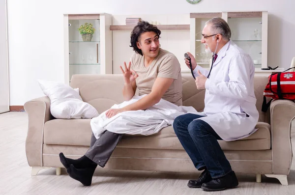 Yaşlı erkek doktor genç erkek hastayı ziyaret ediyor. — Stok fotoğraf