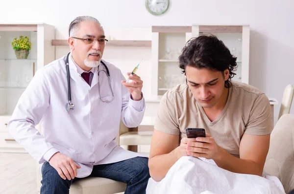 Old male doctor visiting young male patient