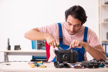 Genç bir erkek müteahhit bilgisayar tamir ediyor.  