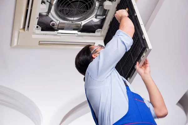 Young repairman repairing ceiling air conditioning unit