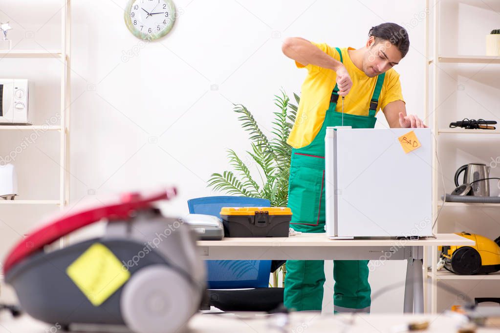 Man repairman repairing vacuum cleaner and fridge 