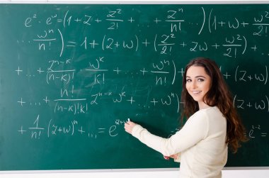 Karatahtanın önünde genç bayan matematik öğretmeni.  