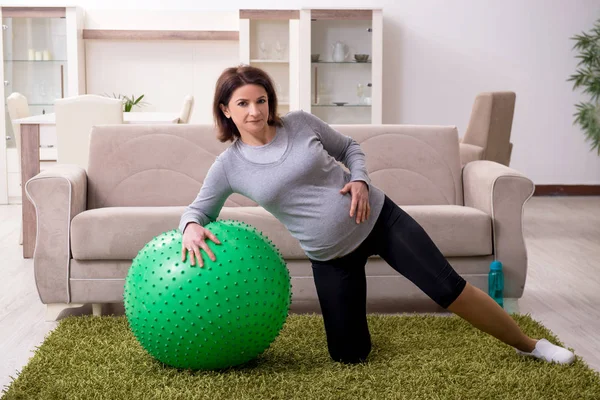 Věk těhotná žena dělá cvičení doma — Stock fotografie