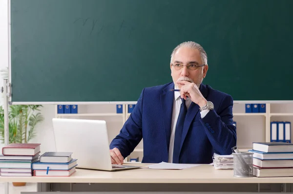 Aged male teacher in front of chalkboard — Stock Photo, Image