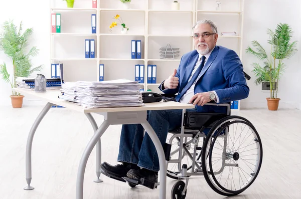 Aged employee in wheelchair working in the office — Stock Photo, Image