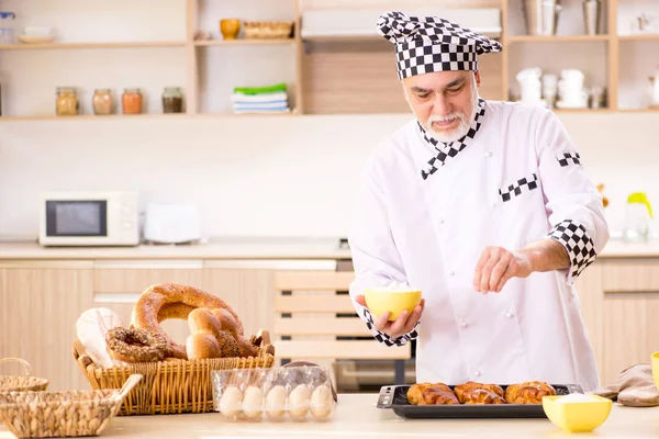 Old male baker working in the kitchen