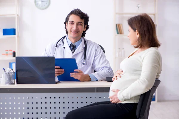 Vieja embarazada visitando joven médico masculino —  Fotos de Stock