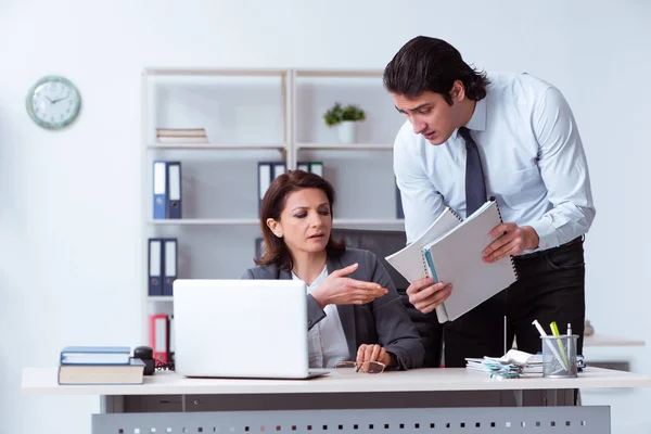 Old female boss and young male employee in the office