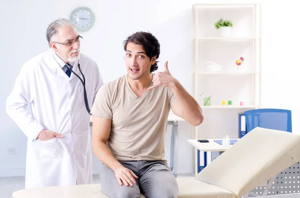 Junge männliche Patientin besucht alten Arzt — Stockfoto