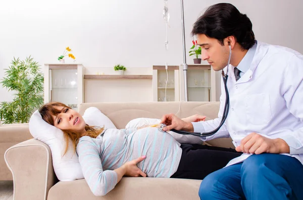 Young handsome doctor visiting pregnant woman at home — Stock Photo, Image