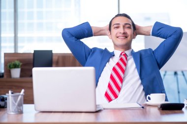 Genç yakışıklı işadamı ofiste oturuyor. 