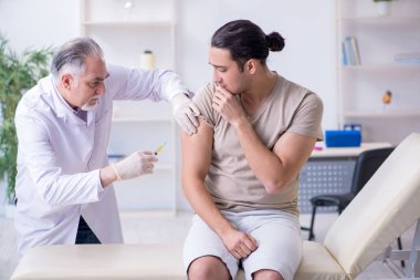 Erkek hasta aşı aşısı için doktoru ziyaret ediyor. 