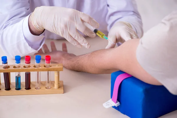 Homem bonito jovem durante o procedimento de amostragem de exames de sangue — Fotografia de Stock