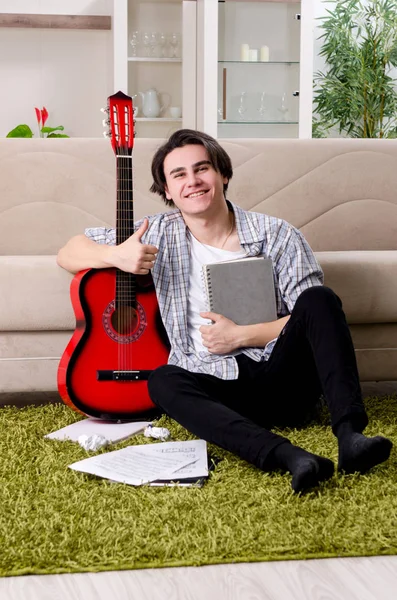 Mladý muž s kytarou doma — Stock fotografie