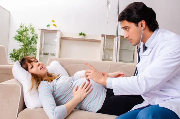 Ung stilig läkare besöker gravid kvinna hemma — Stockfoto