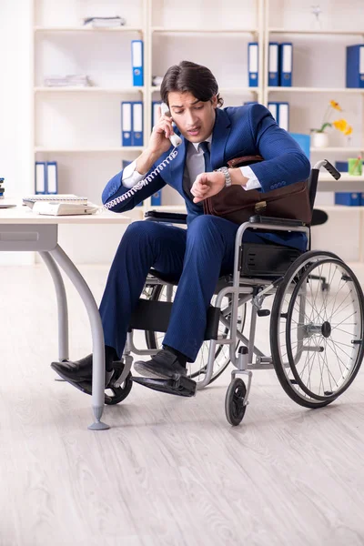Nuori miespuolinen pyörätuolissa työskentelevä työntekijä työskentelee toimistossa — kuvapankkivalokuva