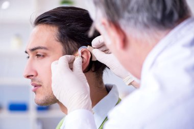 İşitme sorunu olan erkek hasta doktor otorhinolaryng 'i ziyaret ediyor.