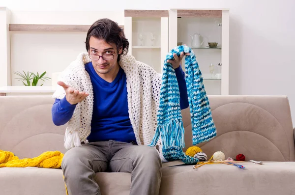 Young good looking man knitting at home