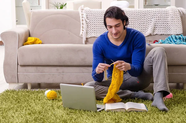 Young good looking man knitting at home