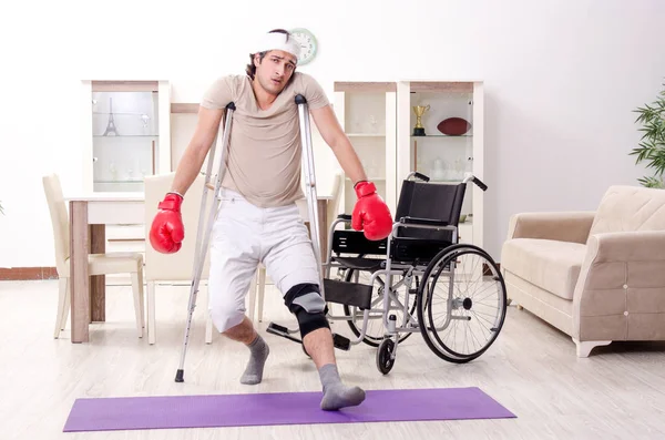 Injured young man doing exercises at home — Stock Photo, Image