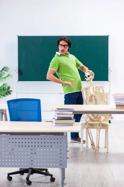 Divertido estudiante masculino en el aula con esqueleto —  Fotos de Stock