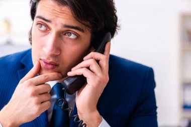 Genç işadamı ofiste oturuyor ve çalışıyor.