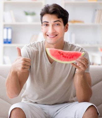 Evde karpuz yiyen bir adam.