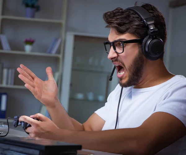 Jovem jogando jogos longas horas atrasado no escritório — Fotografia de Stock