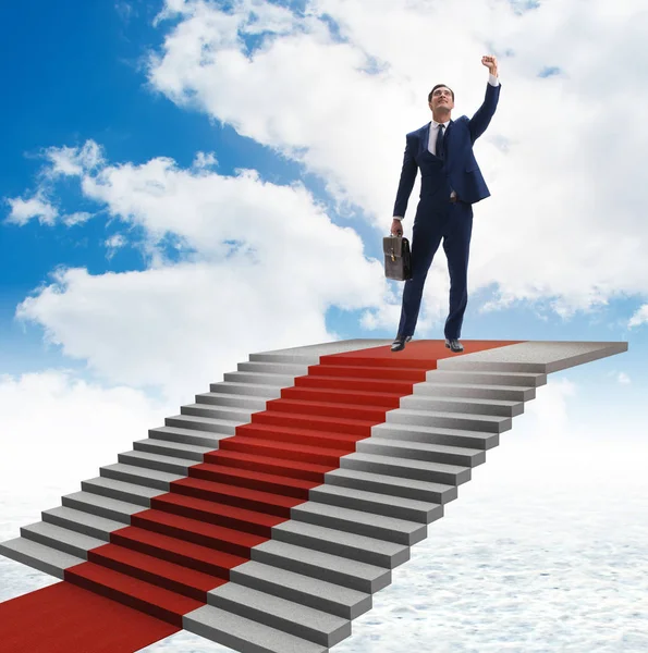 Joven hombre de negocios subiendo escaleras y alfombra roja en el cielo — Foto de Stock