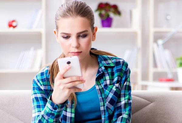 Estudante feminina sentada no sofá com celular — Fotografia de Stock