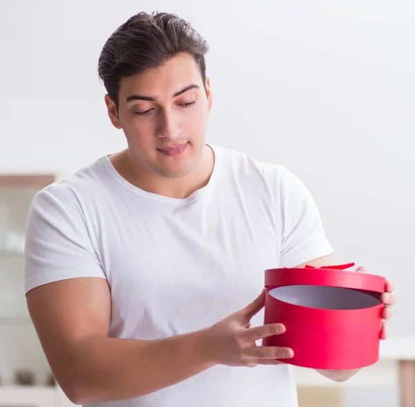 Giovane uomo con sacchetto regalo a casa preparare sorpresa per la moglie — Foto Stock