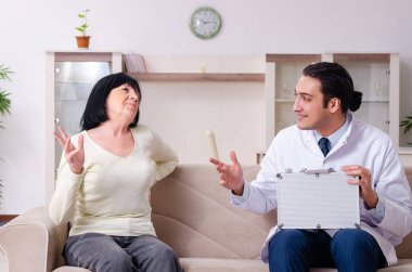 Genç doktor yaşlı yaşlı kadını muayene ediyor.