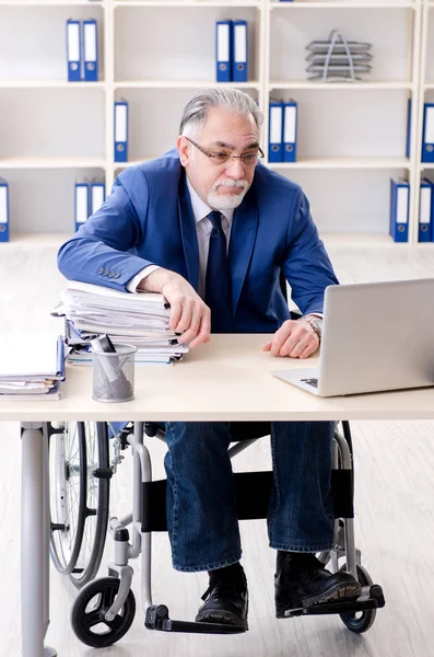 Employé âgé en fauteuil roulant travaillant au bureau — Photo