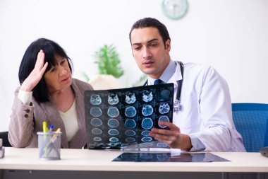 Genç doktor yaşlı yaşlı kadını muayene ediyor.