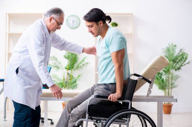 Tekerlekli sandalyedeki erkek hasta yaşlı doktoru ziyaret ediyor. 