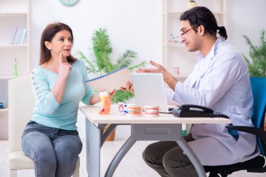 Orta yaşlı bir kadın, erkek doktor stomatoloğu ziyaret ediyor.