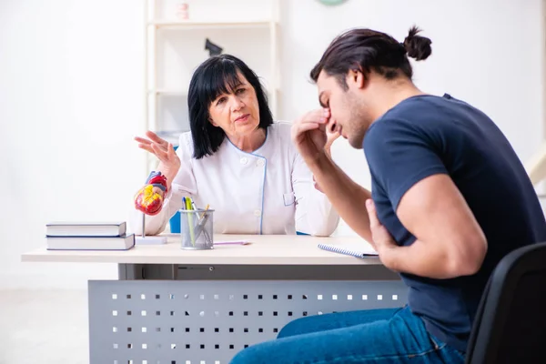 Junge männliche Patientin besucht betagte Ärztin — Stockfoto