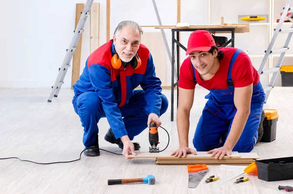 Two professional contractors laying flooring at home