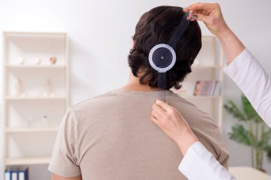 Kadın doktor hastaları goniyometre ile kontrol ediyor.