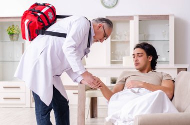 Yaşlı erkek doktor genç erkek hastayı ziyaret ediyor.  