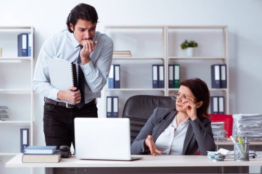 Yaşlı kadın patron ve genç erkek çalışan ofiste.  