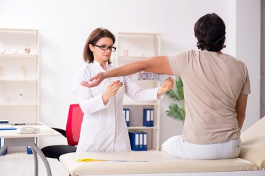 Kadın doktor hastaları goniyometre ile kontrol ediyor.