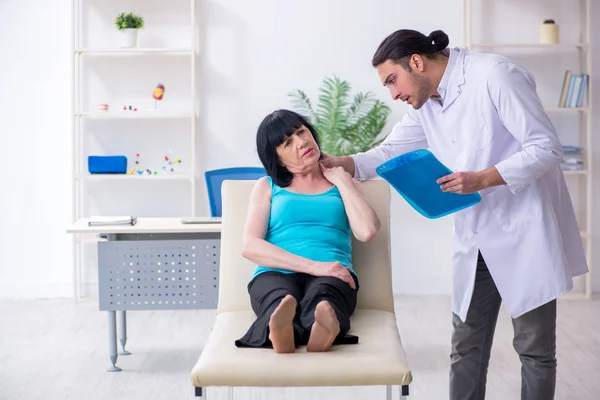 Genç erkek doktor yaşlı kadın hastayı muayene ediyor. — Stok fotoğraf