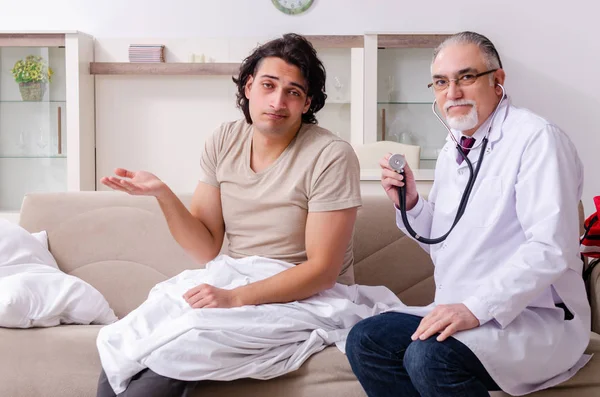 Oude mannelijke arts op bezoek bij jonge mannelijke patiënt — Stockfoto